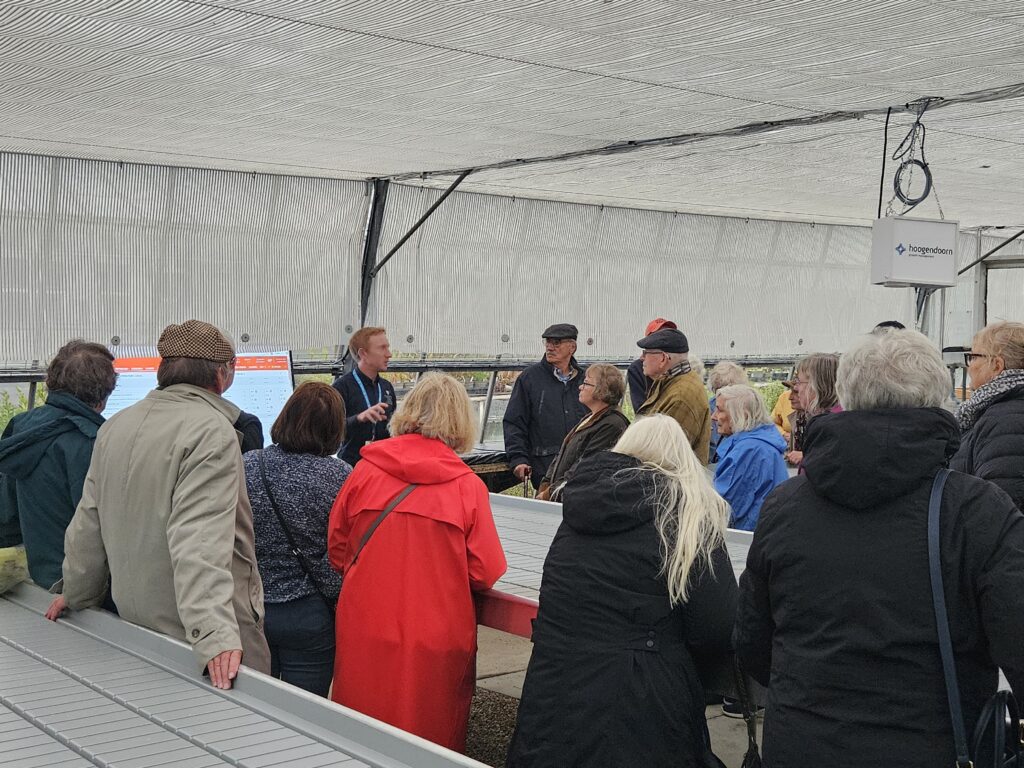A group of adults gathered around a man presenting information on a screen.